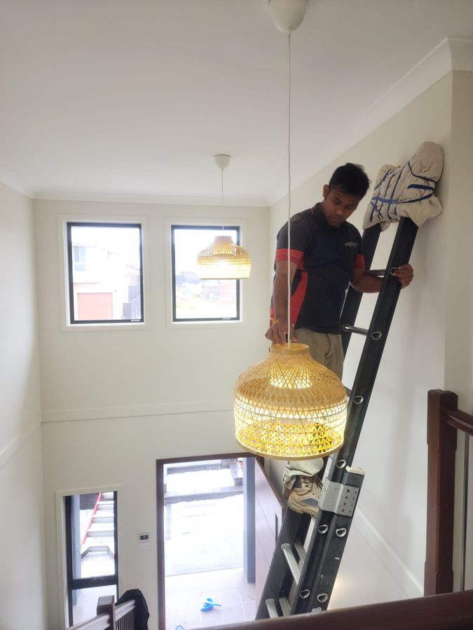 Ranjit installing a pendant light on a high ceiling